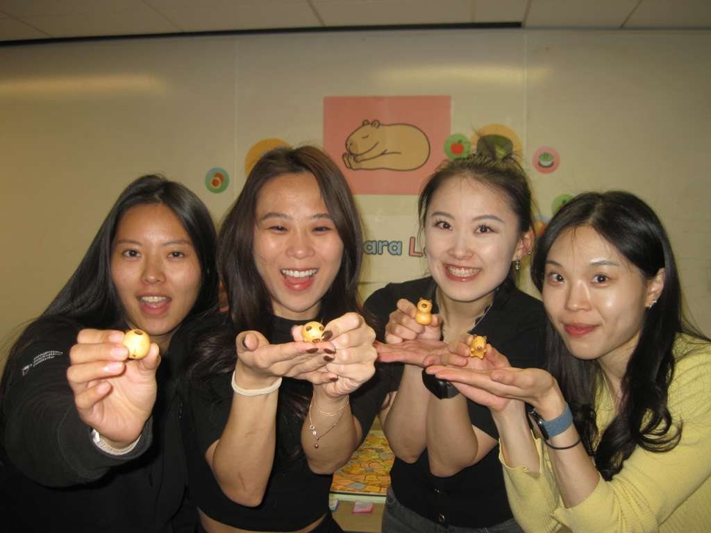 The four-person Capybara Land team holding handmade game pieces beside the final board