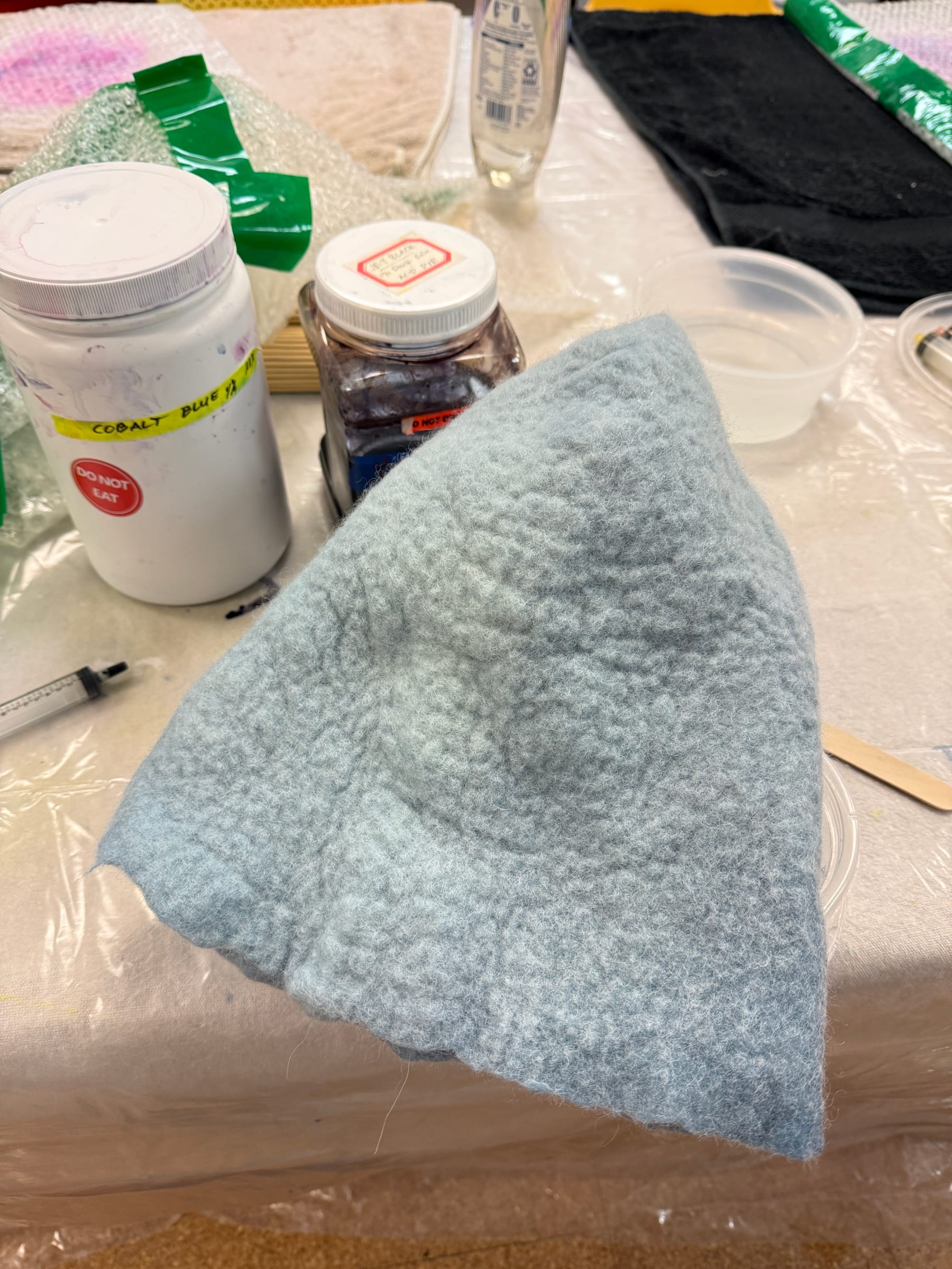 Close view of the felted hat form showing its dense wool texture during coloring